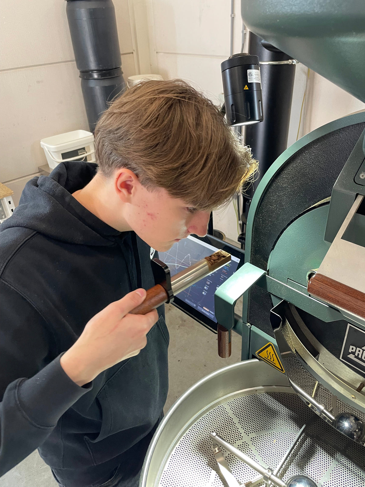 "Jan controleert de kleur en geur van de koffiebonen met een proefschep terwijl ze in de brandmachine roosteren."
